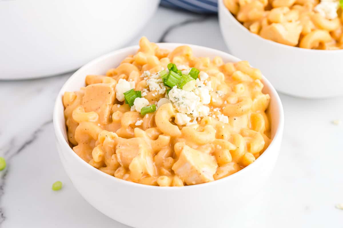 Buffalo Chicken Mac and Cheese in white bowl topped with blue cheese and scallions.