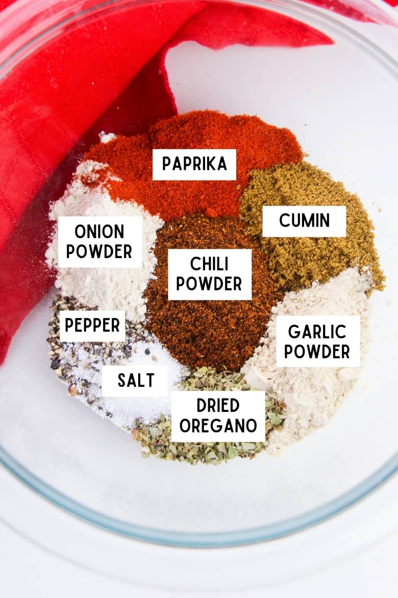 Ingredients for chili seasoning mix in bowl: paprika, cumin, garlic powder, dried oregano, salt, pepper, chili powder, and onion powder.