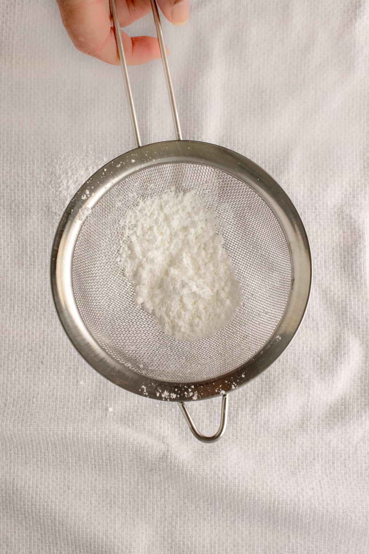 Powdered sugar being sifted on to kitchen towel
