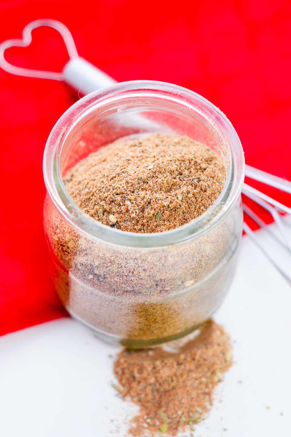 Homemade Chili Seasoning Mix in small glass jar with wire whisk next to it