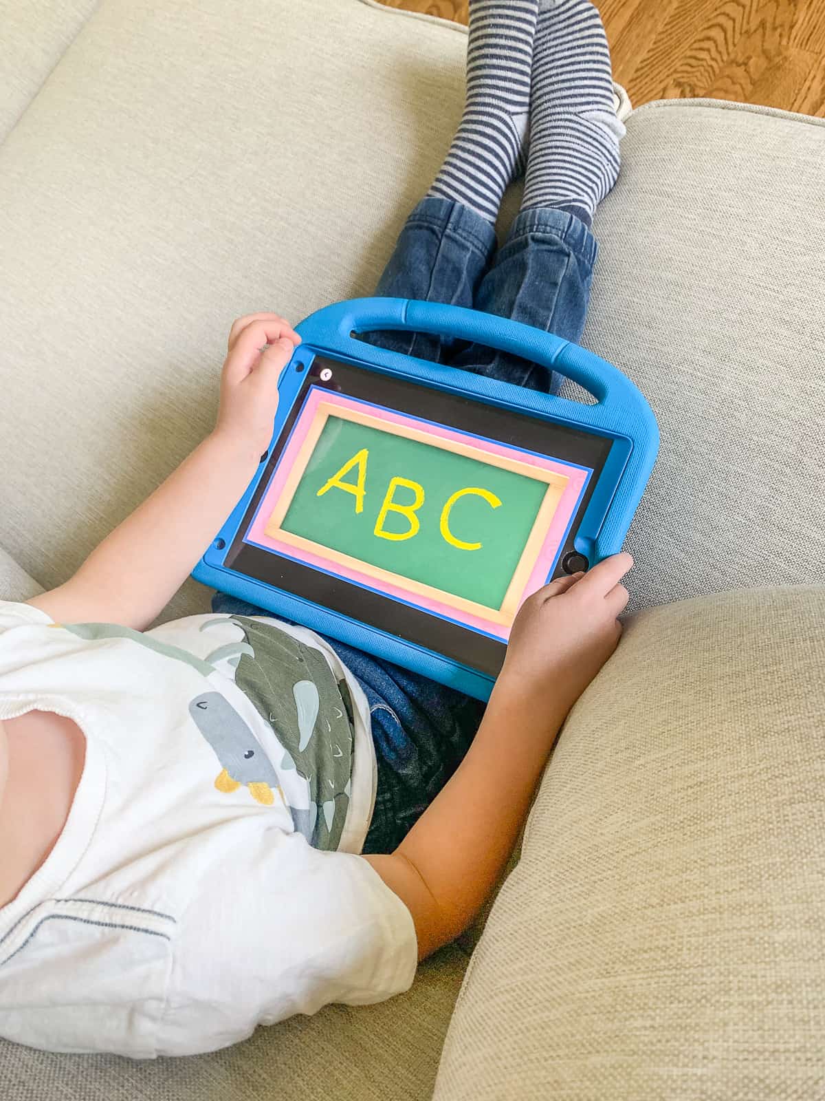 Preschool-age boy sitting and holding ipad with "A, B, C" on screen