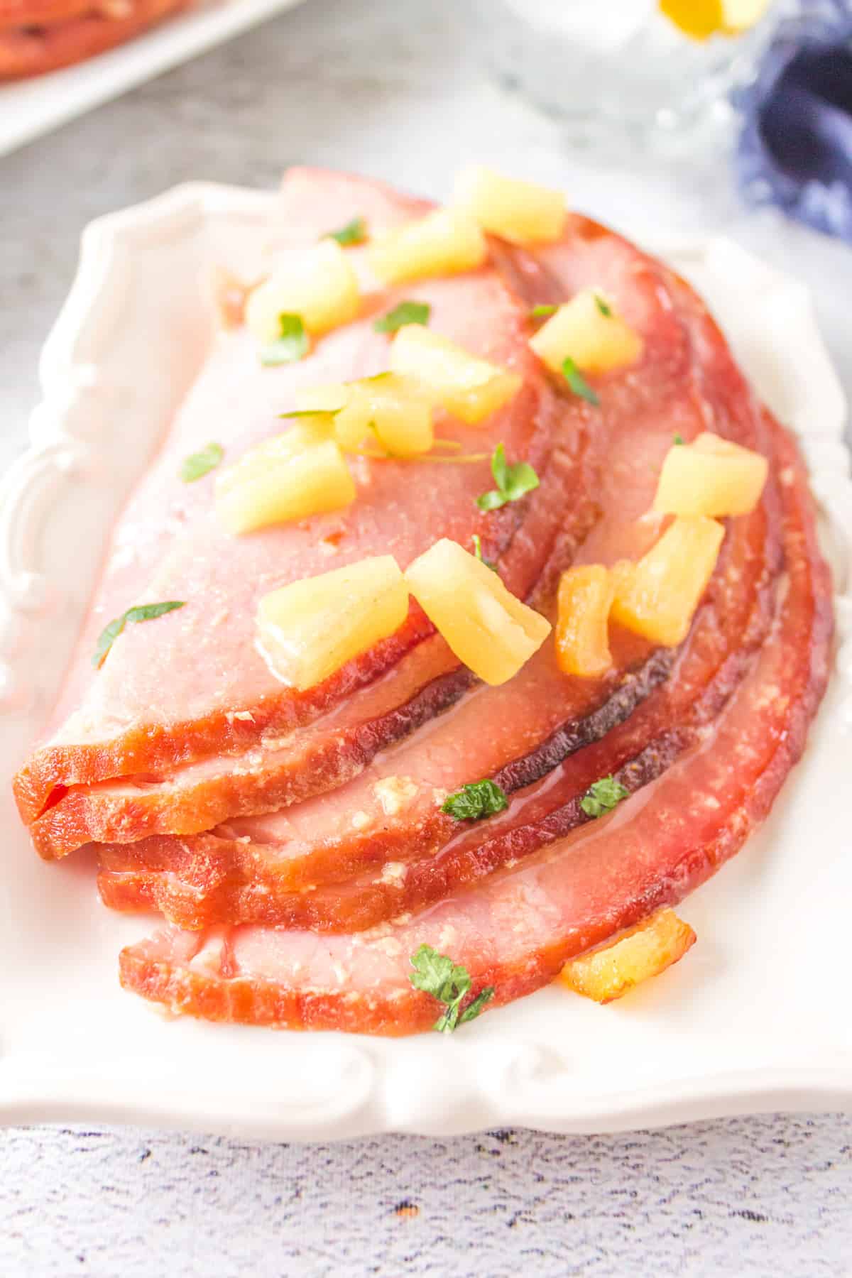 Slices of glazed ham with pineapple chunks on white platter