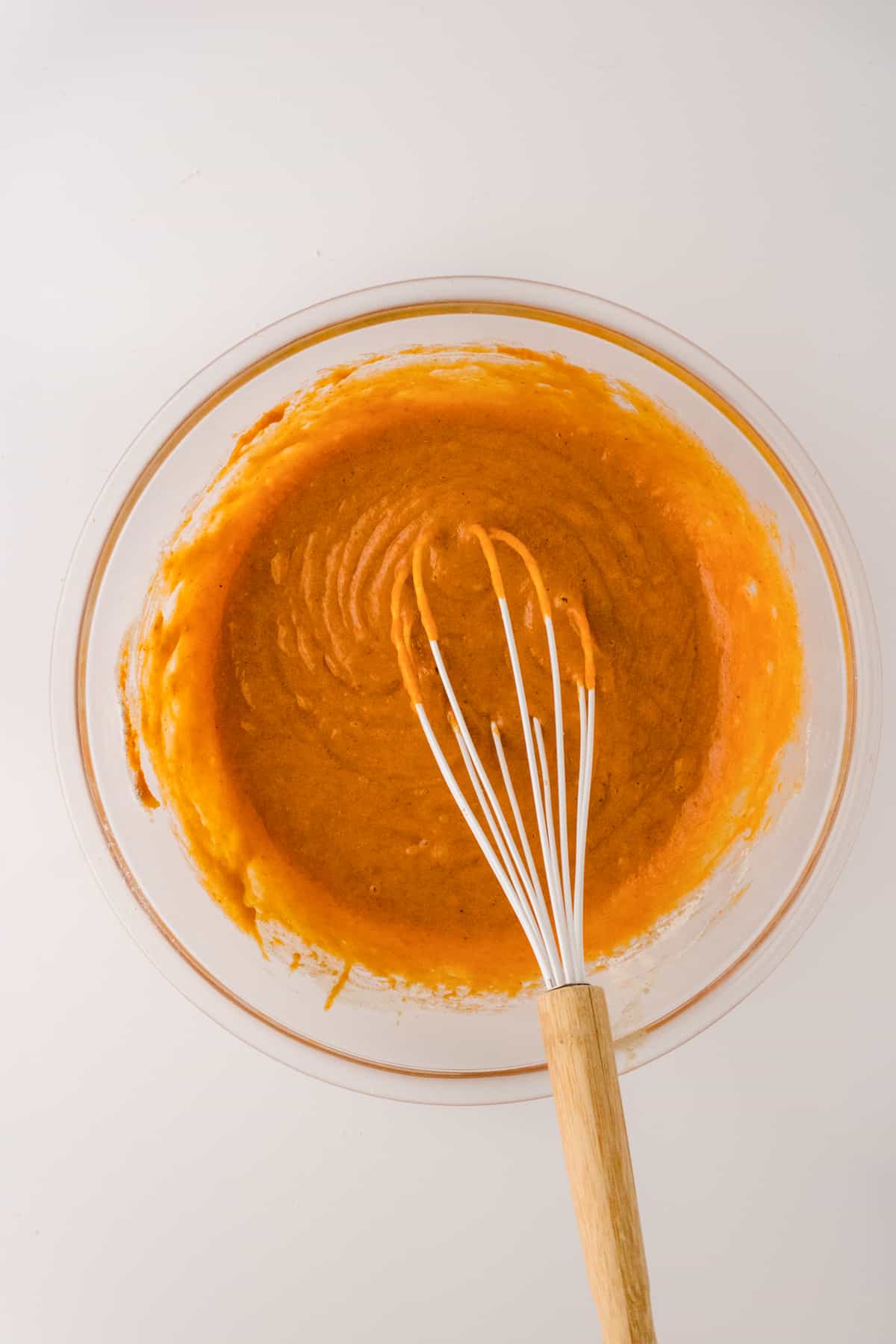 Pumpkin batter in glass bowl with wire whisk