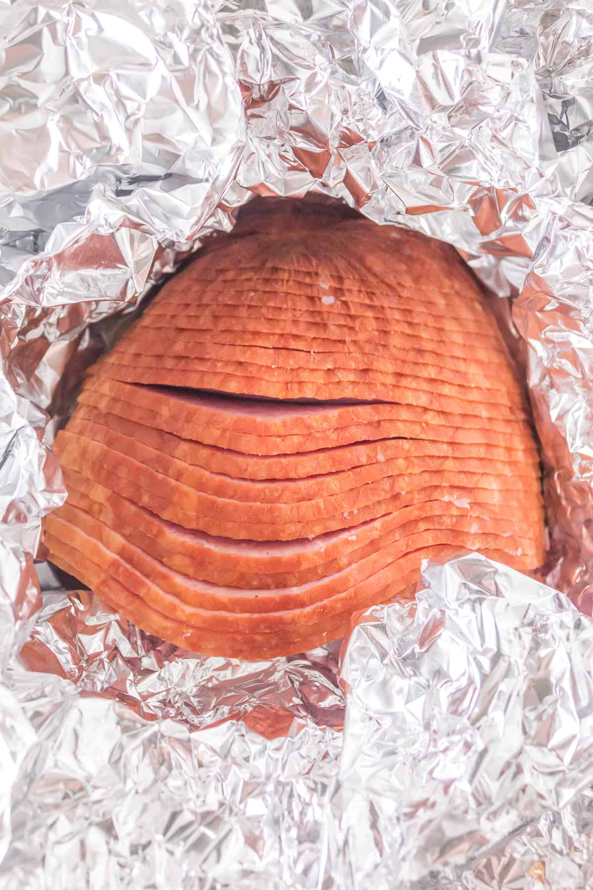 spiral-cut ham wrapped in aluminum foil with top exposed