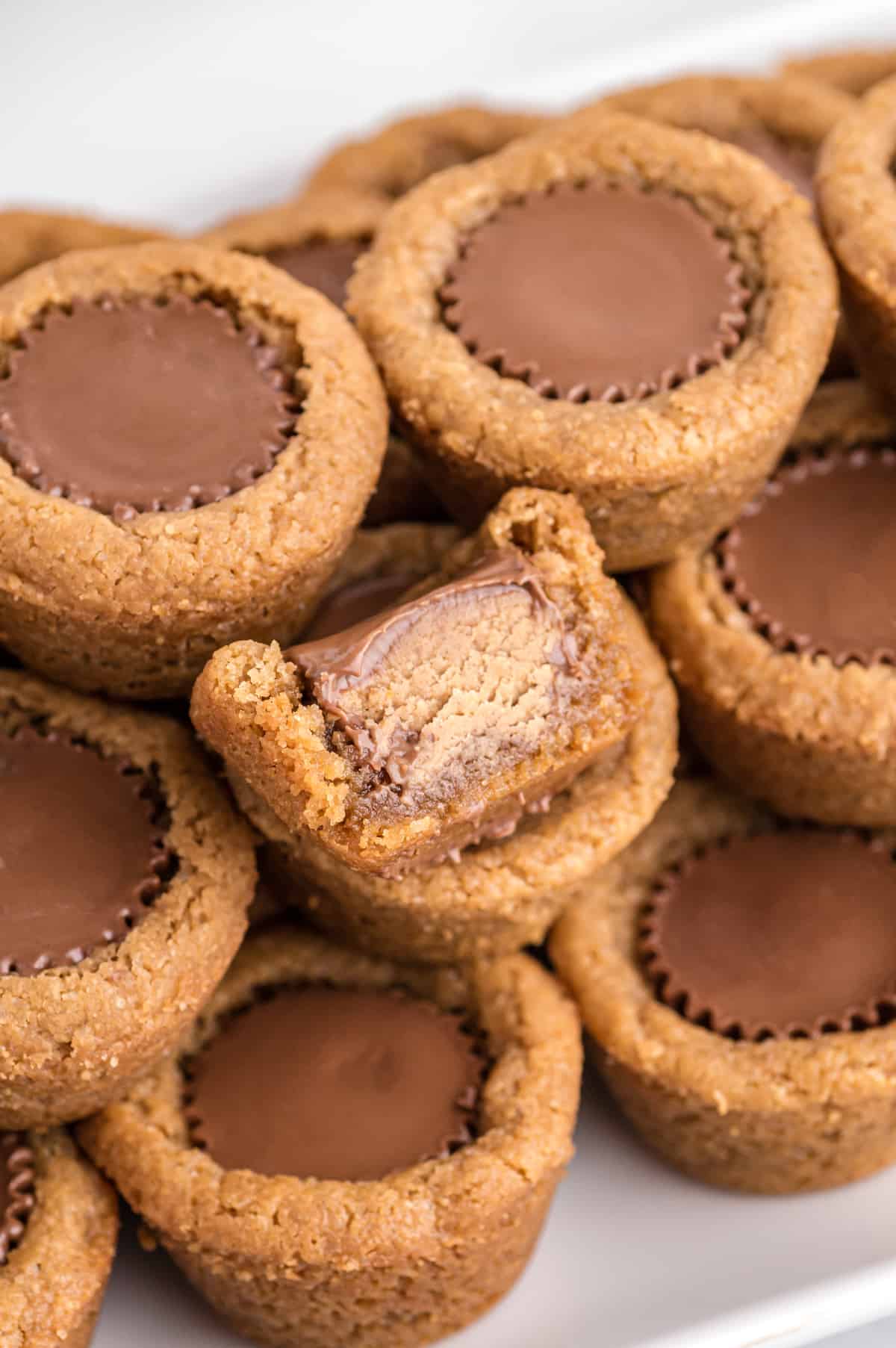 Peanut Butter Cup Cookies with a mini reese's cup in the center. One had bite taken out of it to show inside of reese's peanut butter cup.