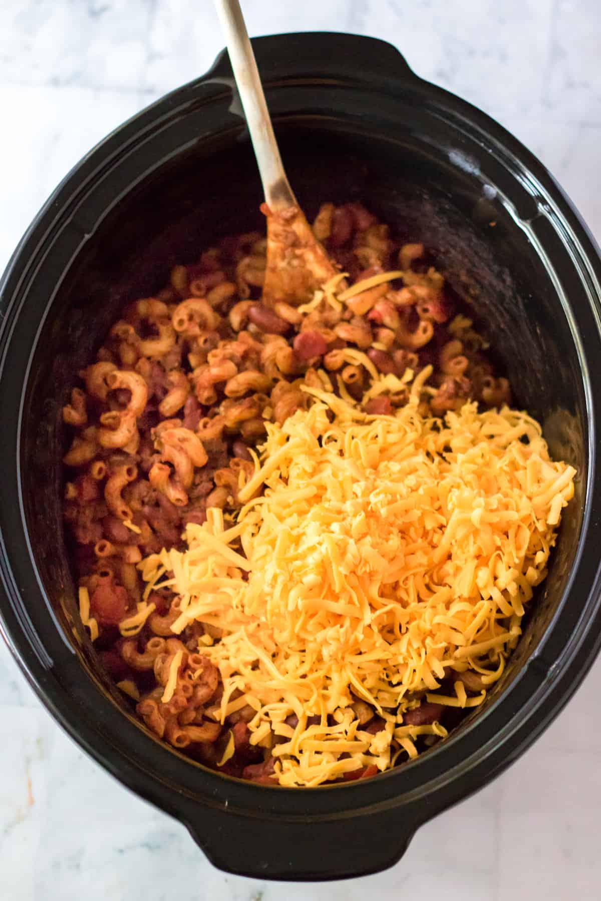 Shredded cheddar cheese added to slow cooker.
