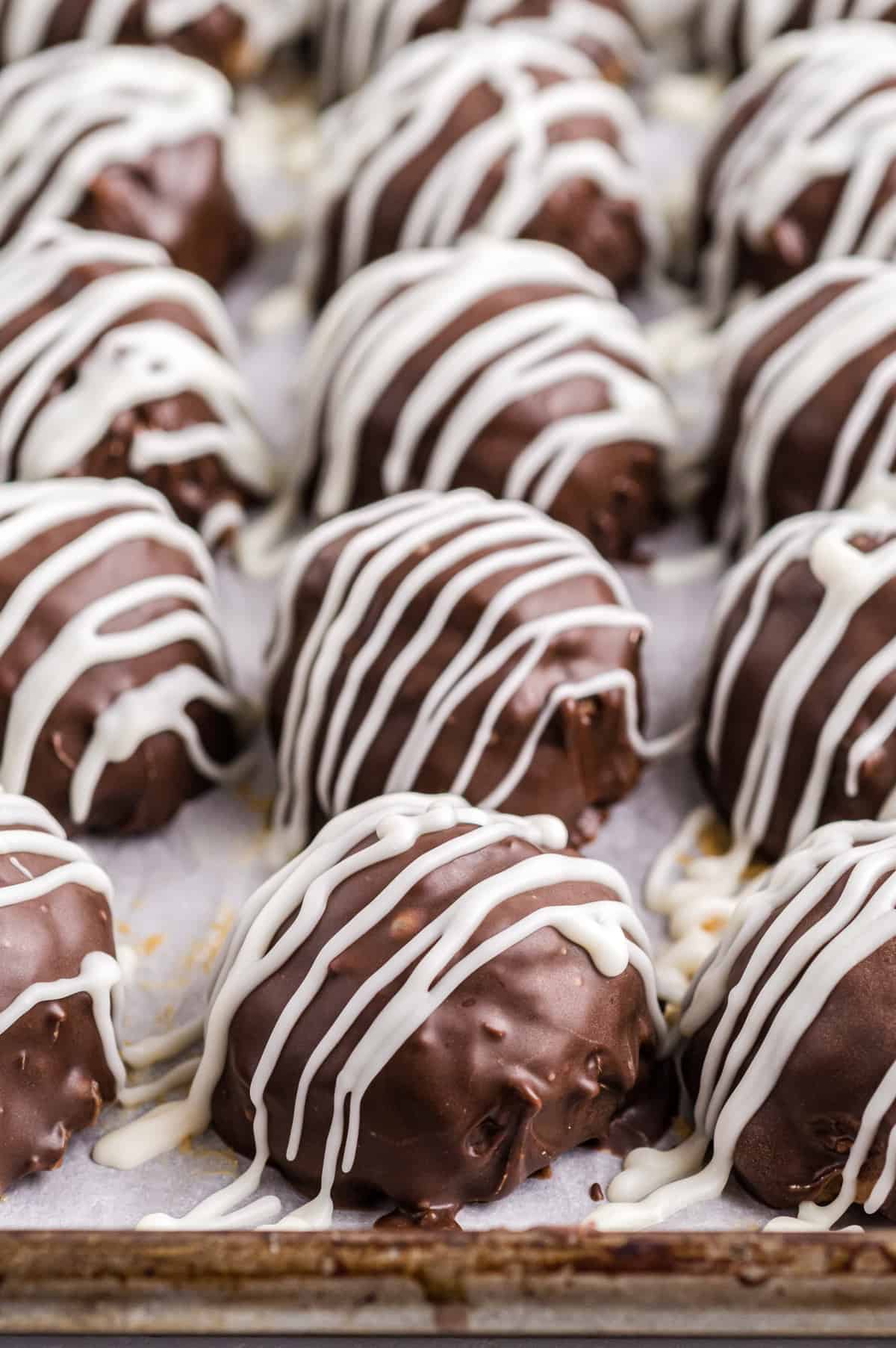 Chocolate Rice Krispies Peanut Butter Balls drizzles with white chocolate on lined baking sheet 