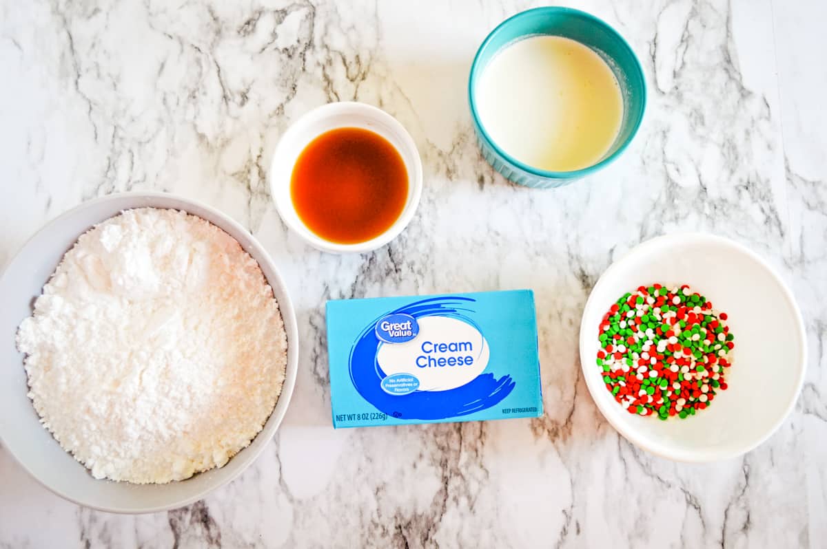 bowl of powdered sugar, bowl of vanilla extract, bowl of heavy whipping cream, bowl of christmas sprinkles, 8 ounce block of great value cream cheese