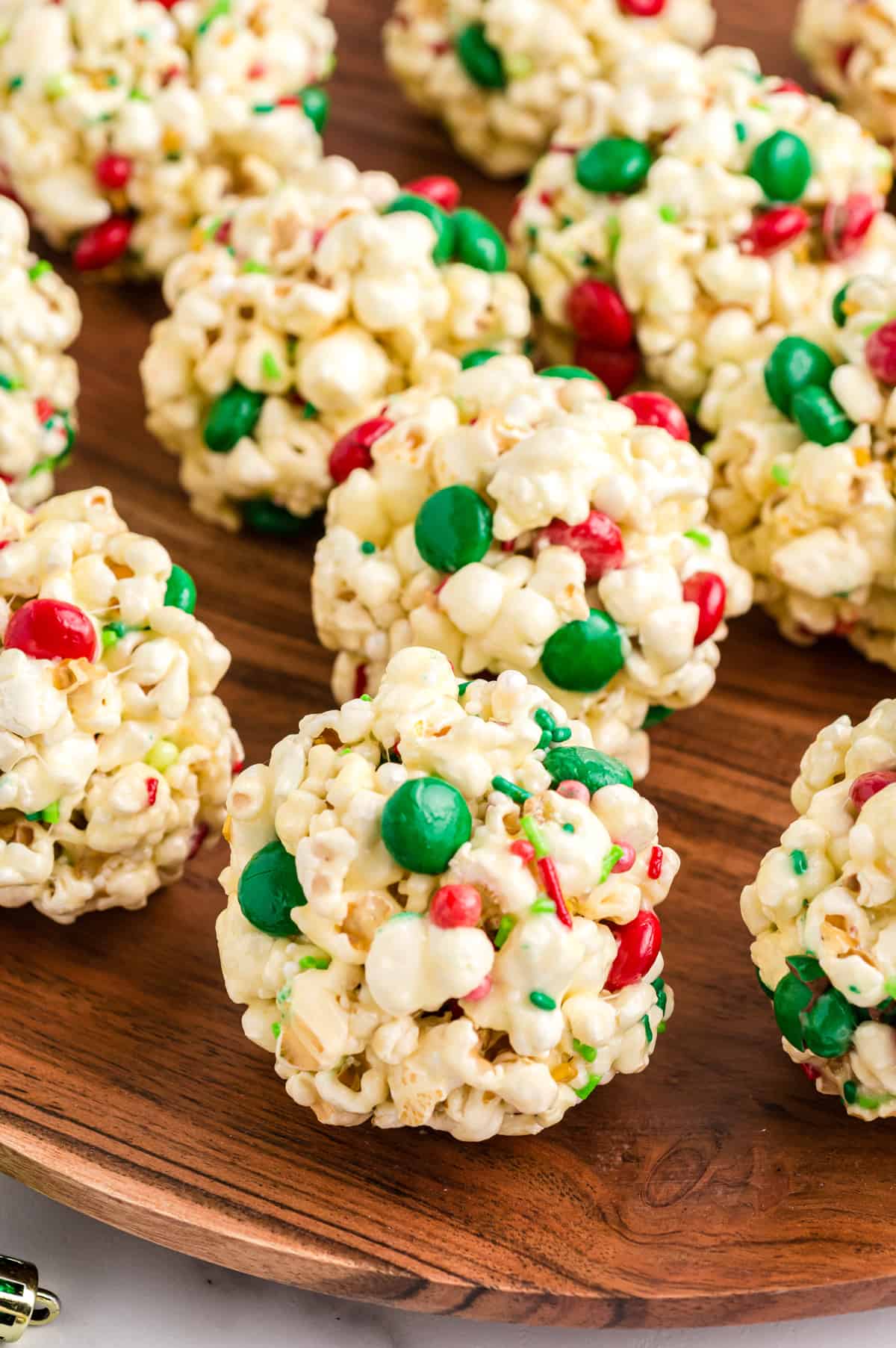 Christmas popcorn balls with marshmallows and red and green M&Ms and sprinkles on wooden serving platter