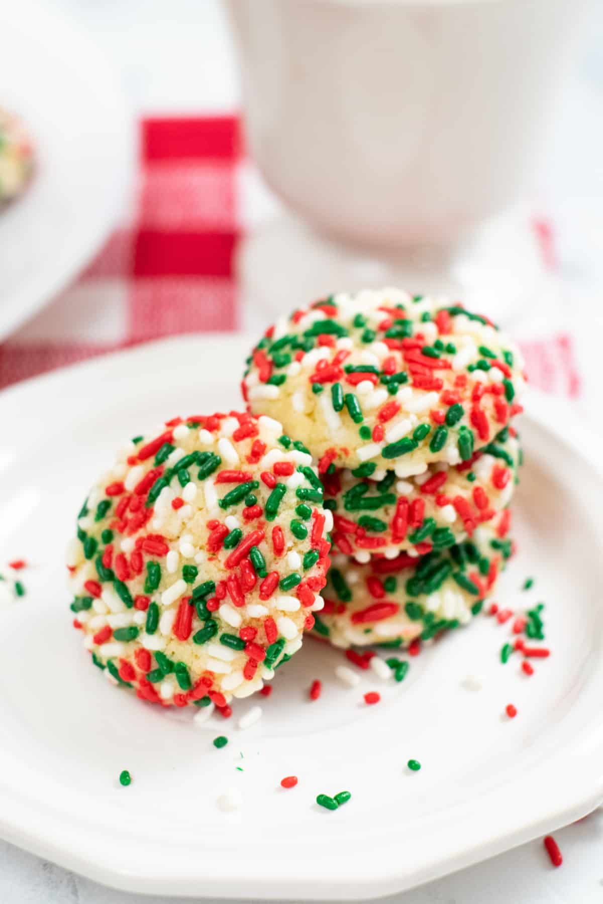 Sprinkle pudding cookies stacked 3 cookies on top of one another, with one cookie leaning on its side.