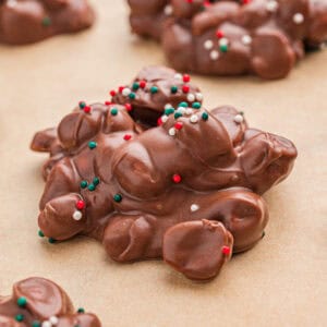 Crock pot candy (aka chocolate peanut clusters) with Christmas sprinkles on parchment paper.