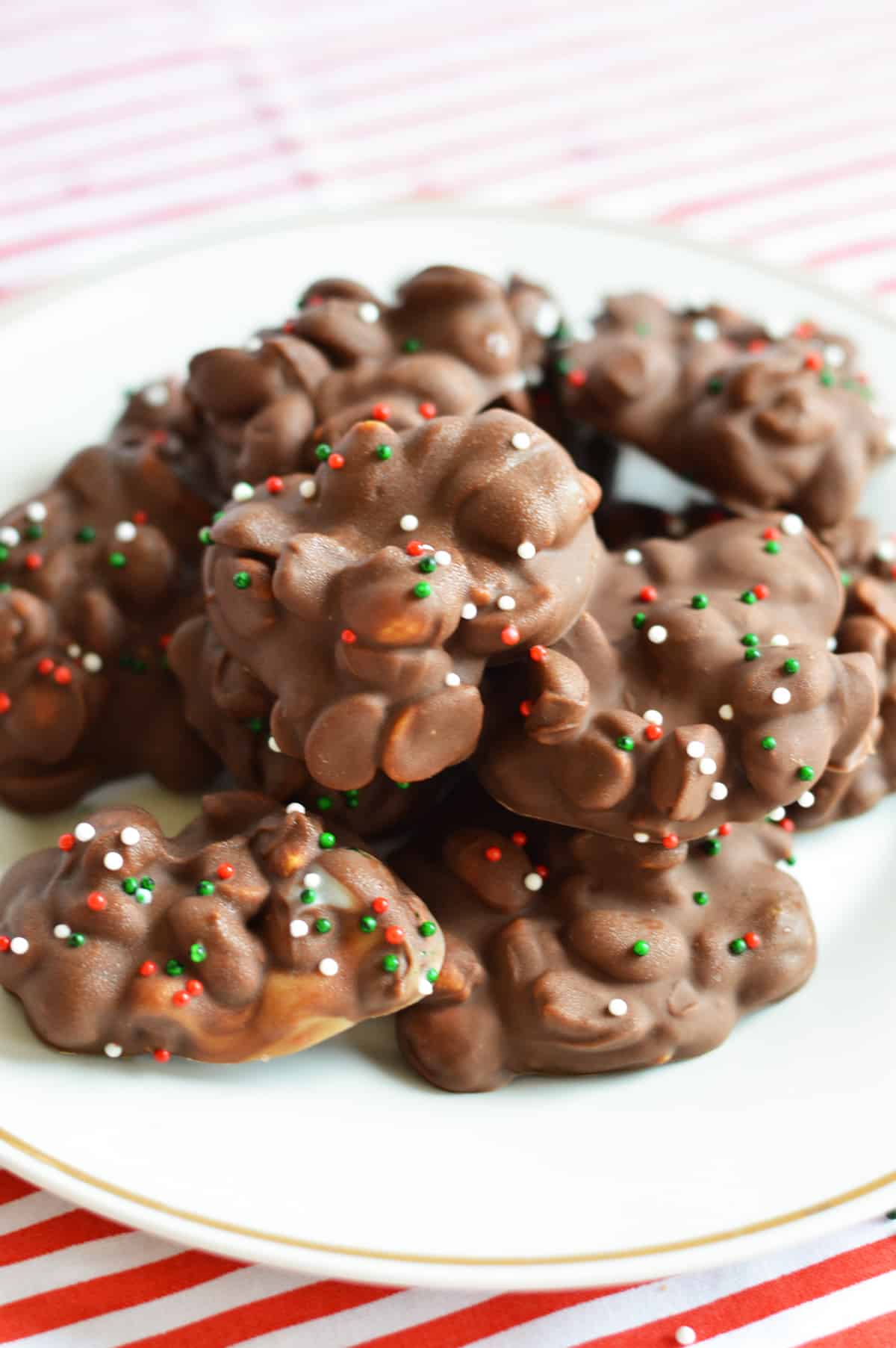 Crockpot candy with peanuts and christmas sprinkles on white plate