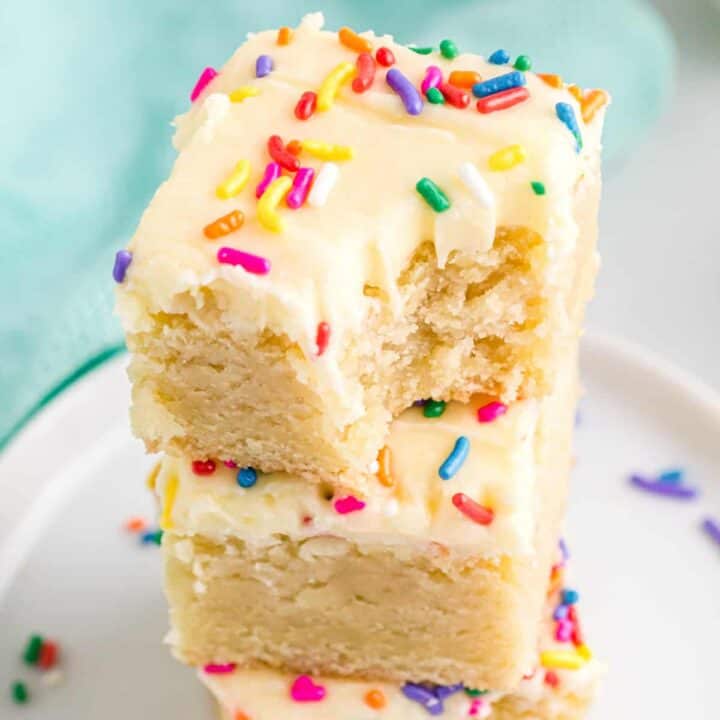 frosted sugar cookie bars stacked on top of each other, with a bite taken out of the top one