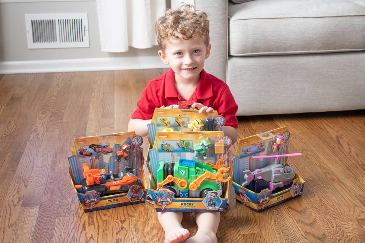 Young boy with PAW Patrol Movie Deluxe Vehicles in packaging