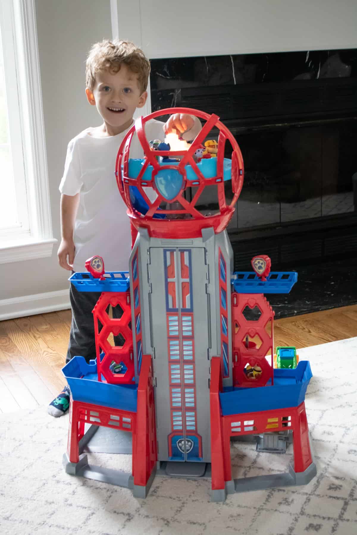 Young boy excited and smiling behind the The Ultimate City Tower Playset