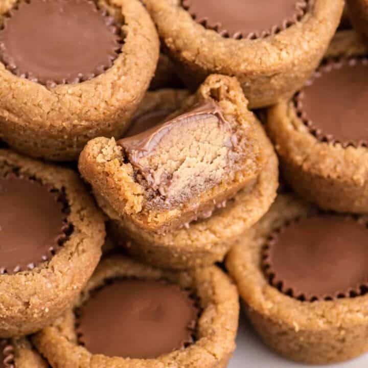 Peanut Butter Cup Cookies with a mini reese's cup in the center. One had bite taken out of it to show inside of reese's peanut butter cup.