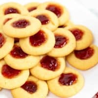 Thumbprint cookies with jam centers piled on a white plate