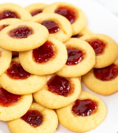 Thumbprint cookies with jam centers piled on a white plate