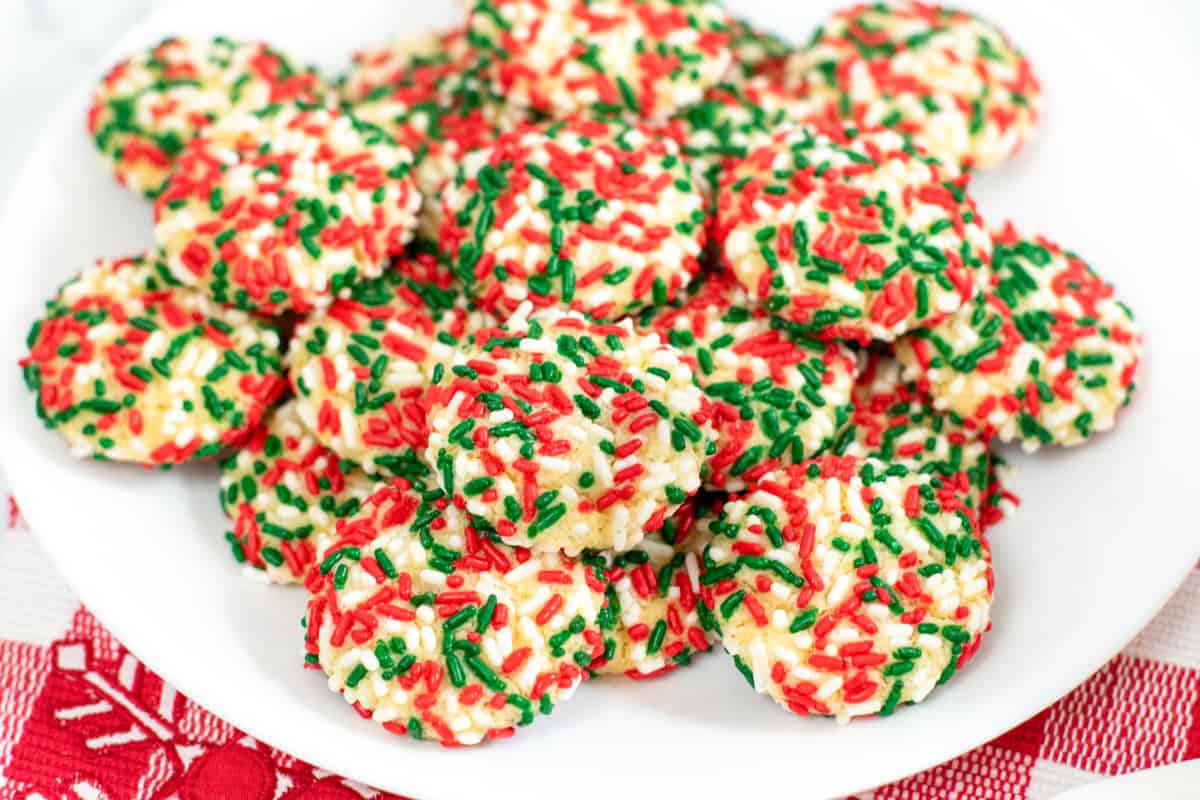 Round cookies with red, green and white sprinkles stacked on a serving plate
