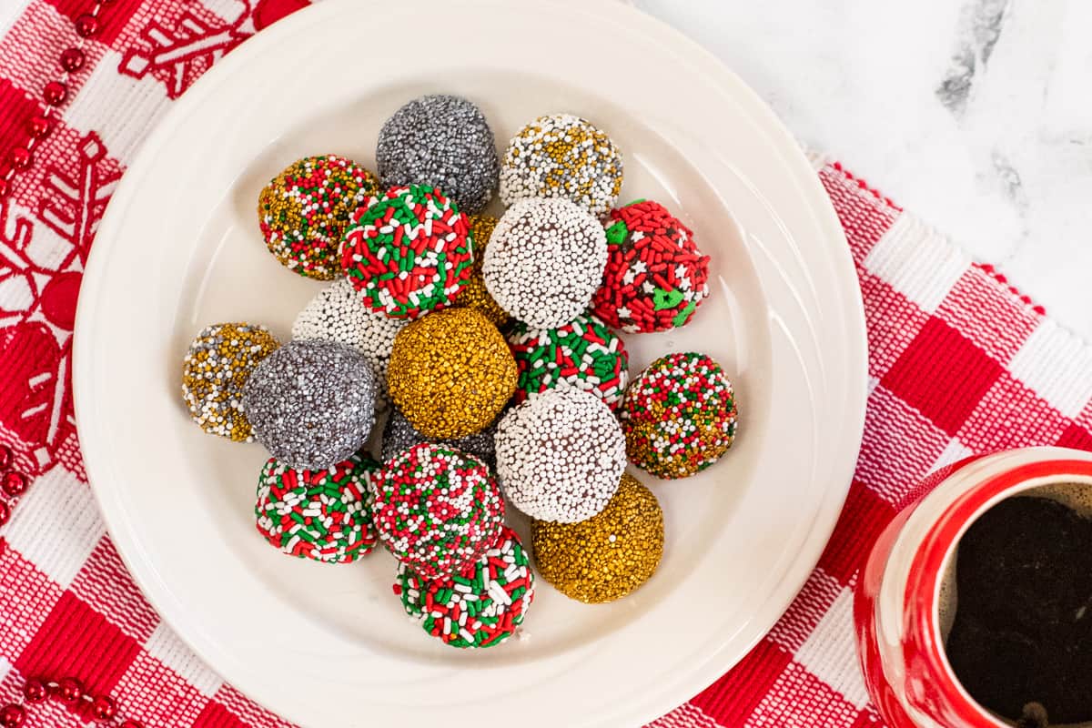 no-bake brownie batter truffles decorated with holiday sprinkles on white plate