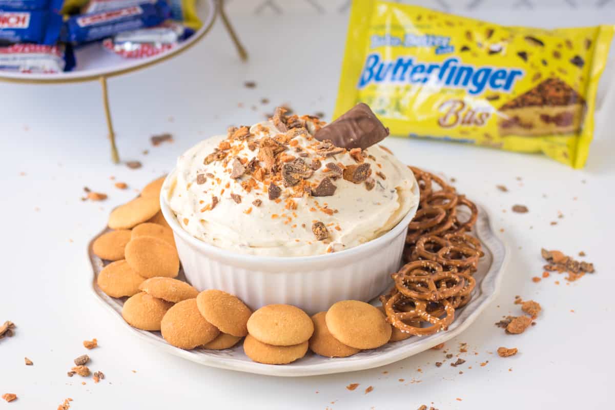 Butterfinger Fluff with Butterfinger Candy Bar sticking out of the top and Butterfinger Baking Bits in the background