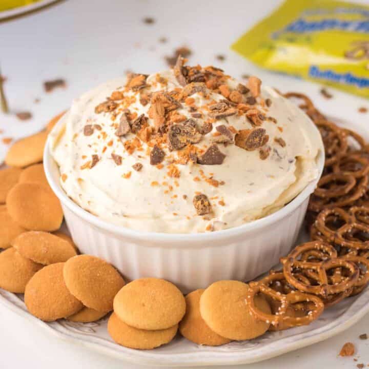 Butterfinger Candy Bar dessert dip with vanilla wafers and pretzels for dipping. Butterfinger candy bars and crunch bars in background.