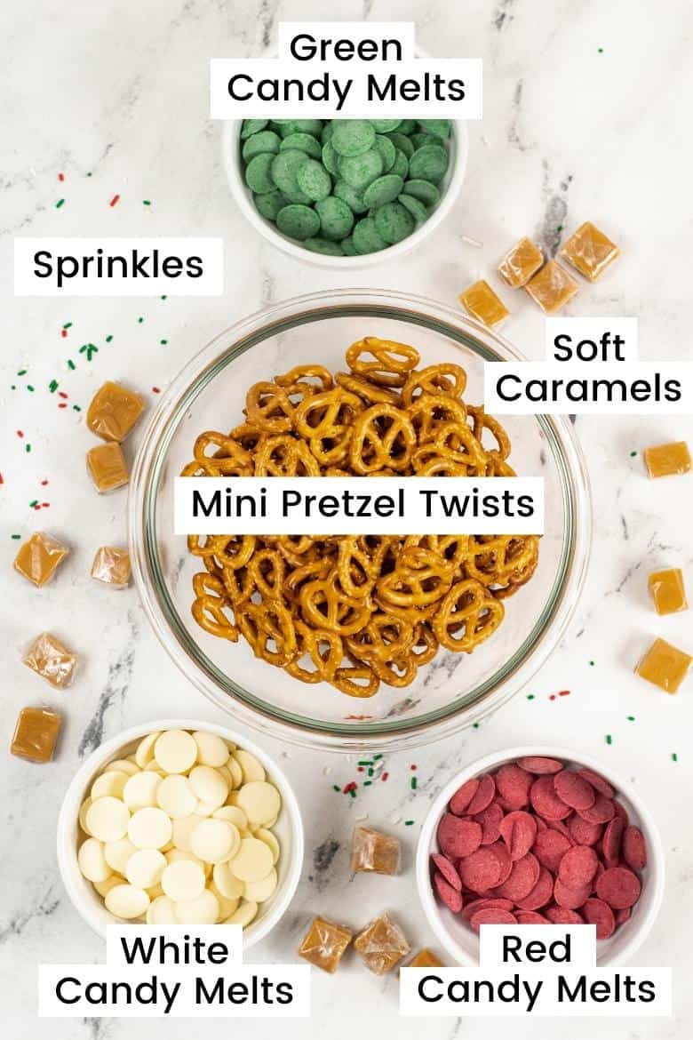 Labeled ingredients on countertop:  green candy melts, soft caramels, pretzel twists, red candy melts, white candy melts, sprinkles 