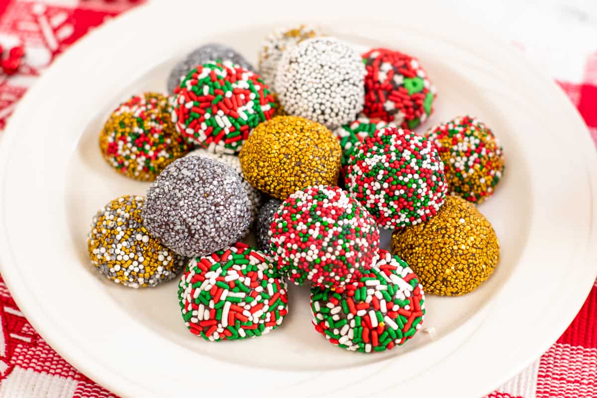 no-bake brownie batter truffles decorated with holiday sprinkles on white plate