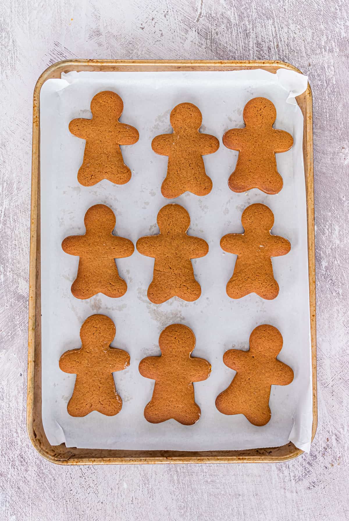 undecorated gingerbread men cookies on parchment-lined baking sheet