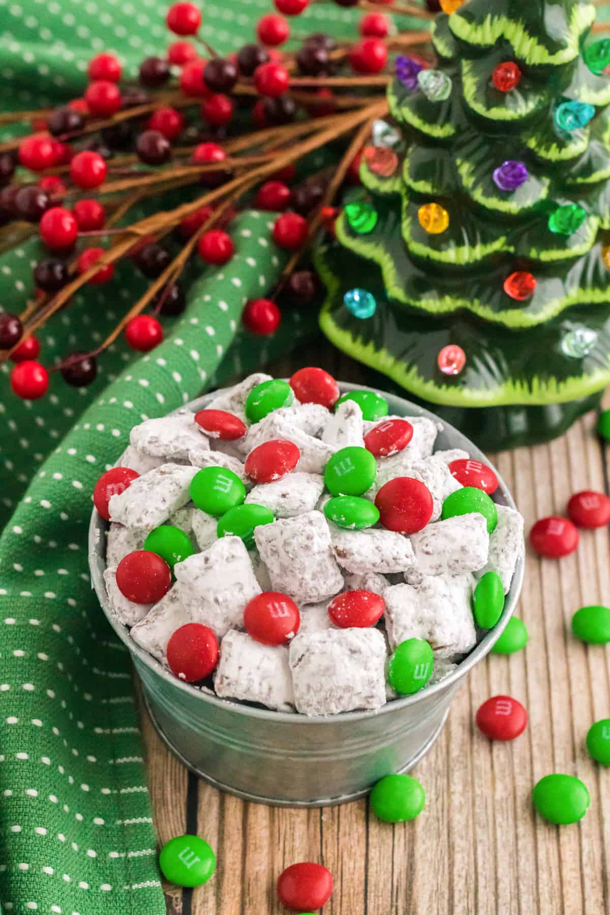small bowl of reindeer chow with holiday M&Ms on a table with christmas decorations