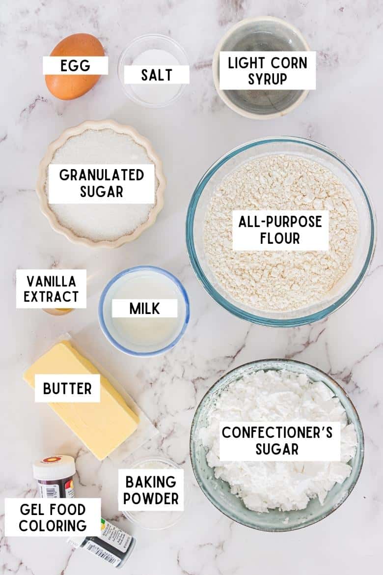 Ingredients on countertop: one brown egg, salt, light corn syrup, granulated sugar, all-purpose flour, vanilla extract, milk, butter, confectioners sugar, baking powder, gel food coloring