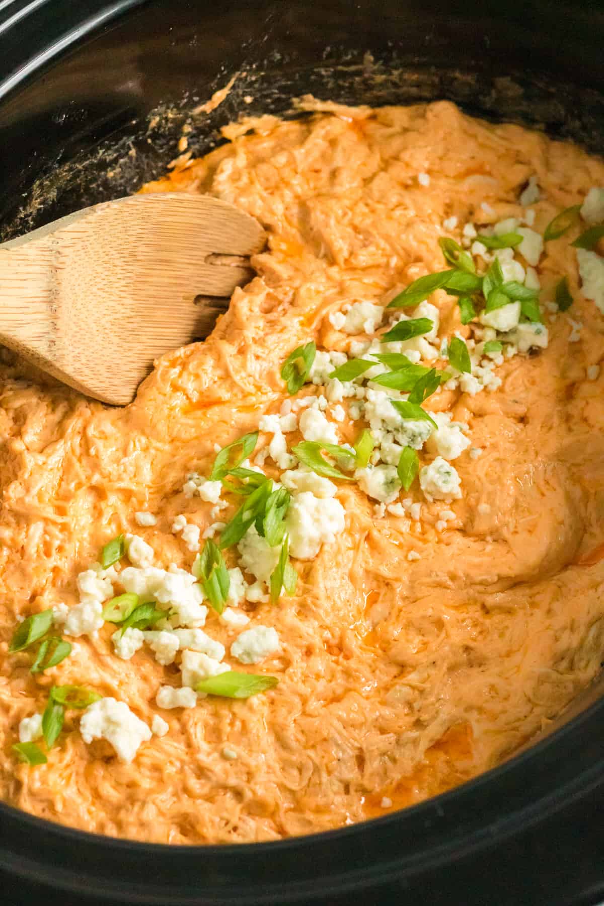 Crockpot buffalo chicken dip with blue cheese and green onions on top