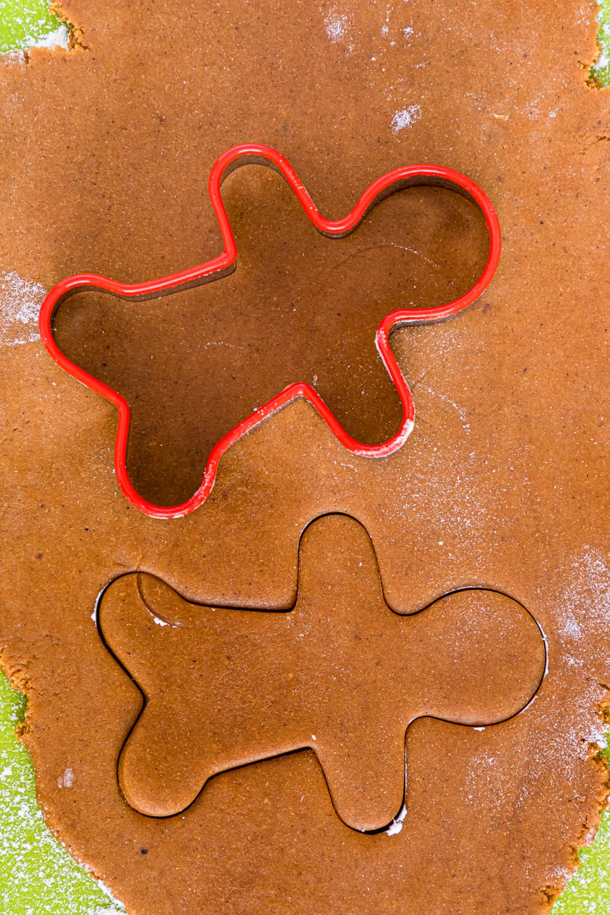 man shaped cookie cutter cutting gingerbread cookie dough