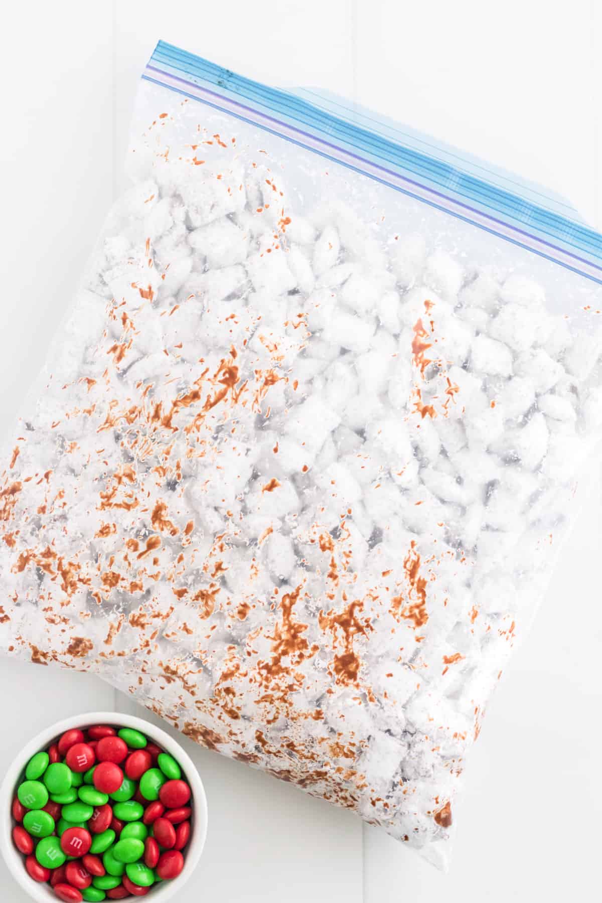 Gallon-size ziplock bag with muddy buddies inside. Bowl of red and green M&Ms are next to it.