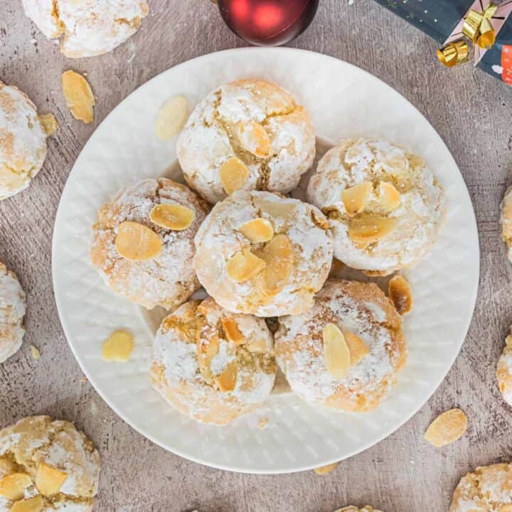 Soft Amaretti Cookies piled on a white plate surrounded by more cookies