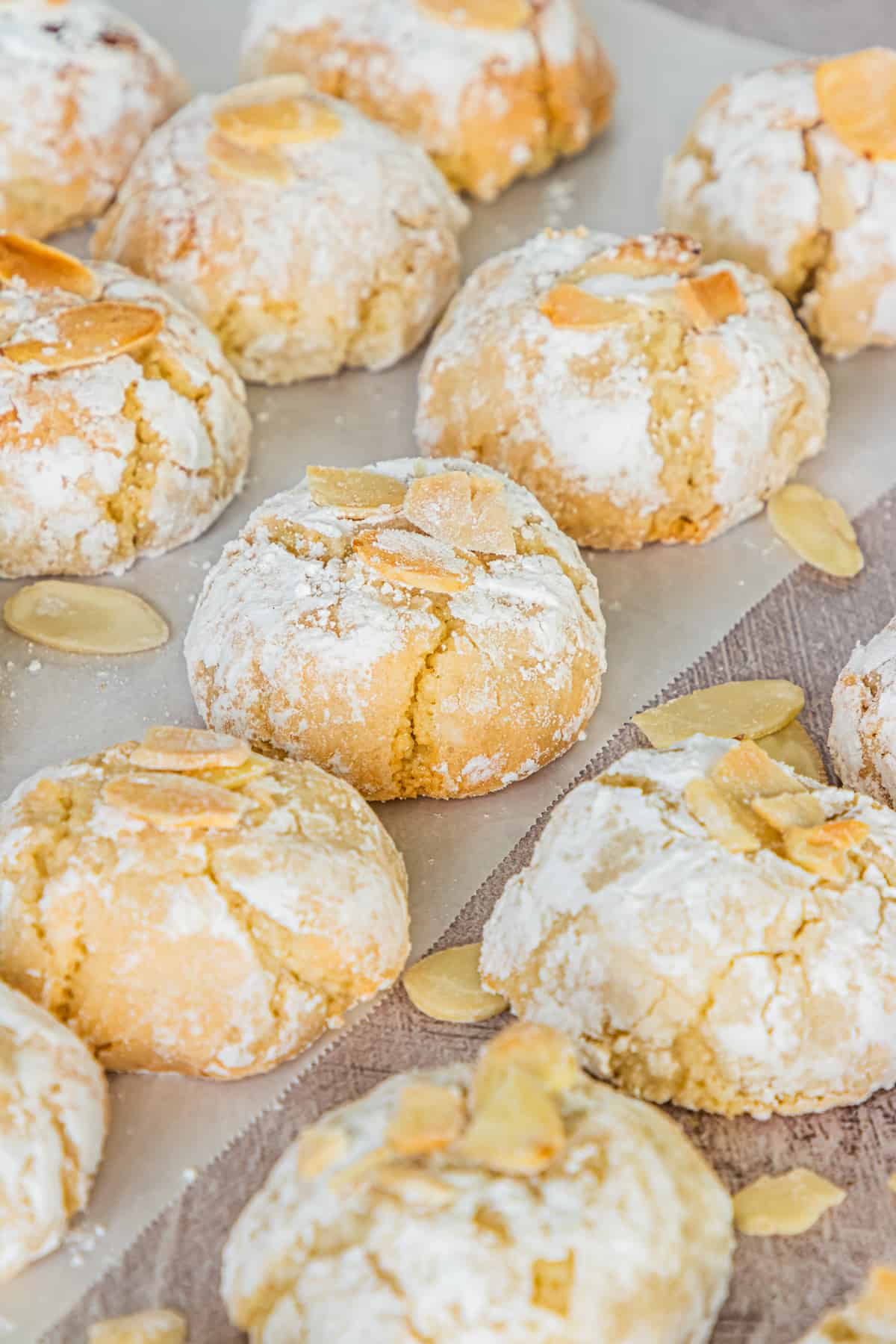Soft Italian Amaretti Cookies with flaked almonds lined up neatly on parchment paper