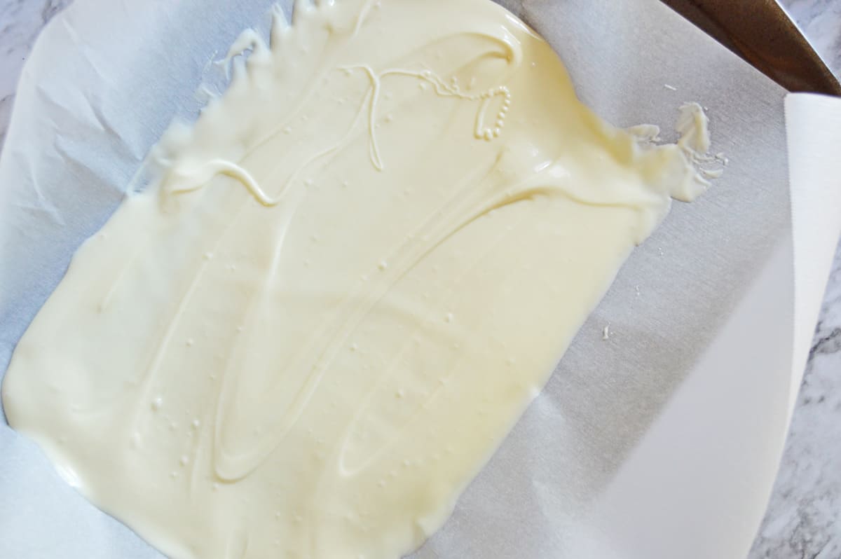 melted white candy spread onto parchment lined baking sheet