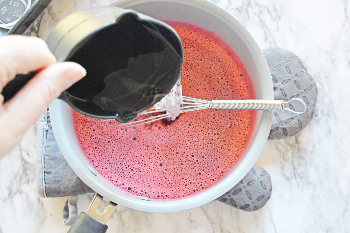 Vodka being poured into bowl of strawberry jello