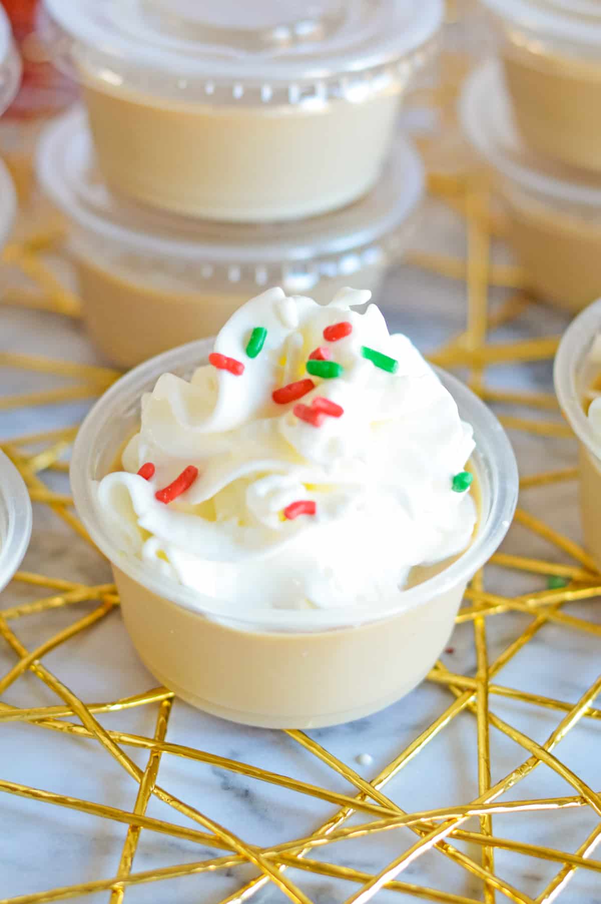 Christmas sugar cookie jello shot topped with whipped cream and red and green jimmies