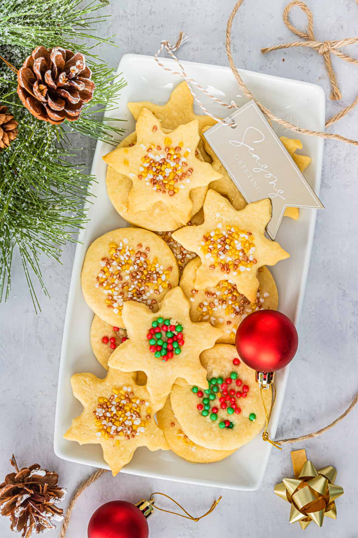 Christmas Shortbread Cookies with sprinkles on serving platter with christmas decor around them