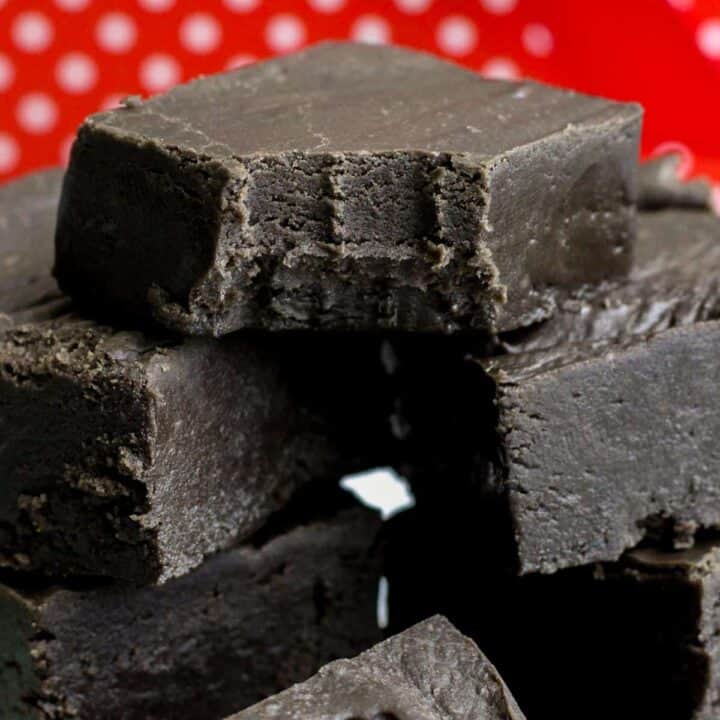 Black fudge cut in squares and stacked in a pile. The top piece has a bite taken out of it.