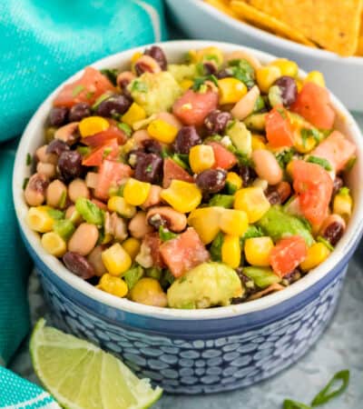 Cowboy Caviar dip with beans, avocado, corn, scallions, and dressing in a bowl, served with tortilla chips
