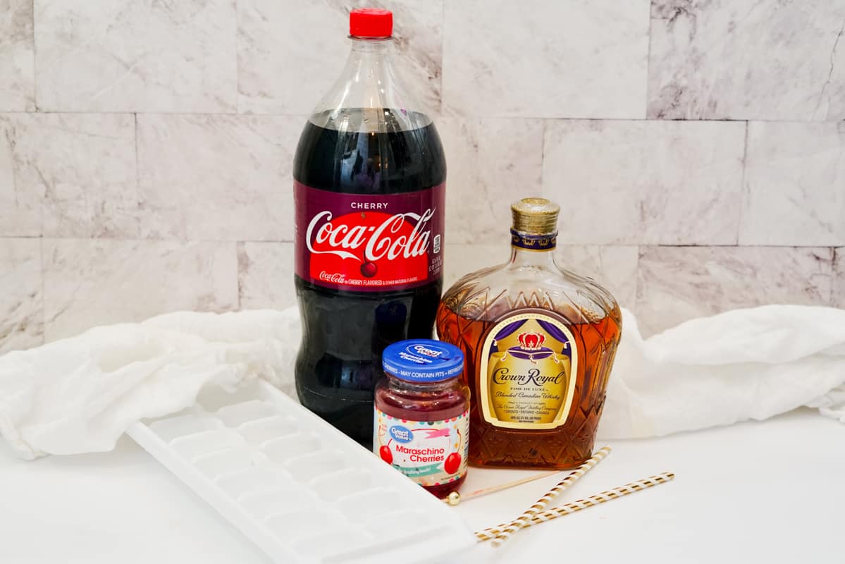 2 Liter bottle of Cherry Coke, bottle of Crown Royal whisky, jar of maraschino cherries, ice cube tray, and paper straws