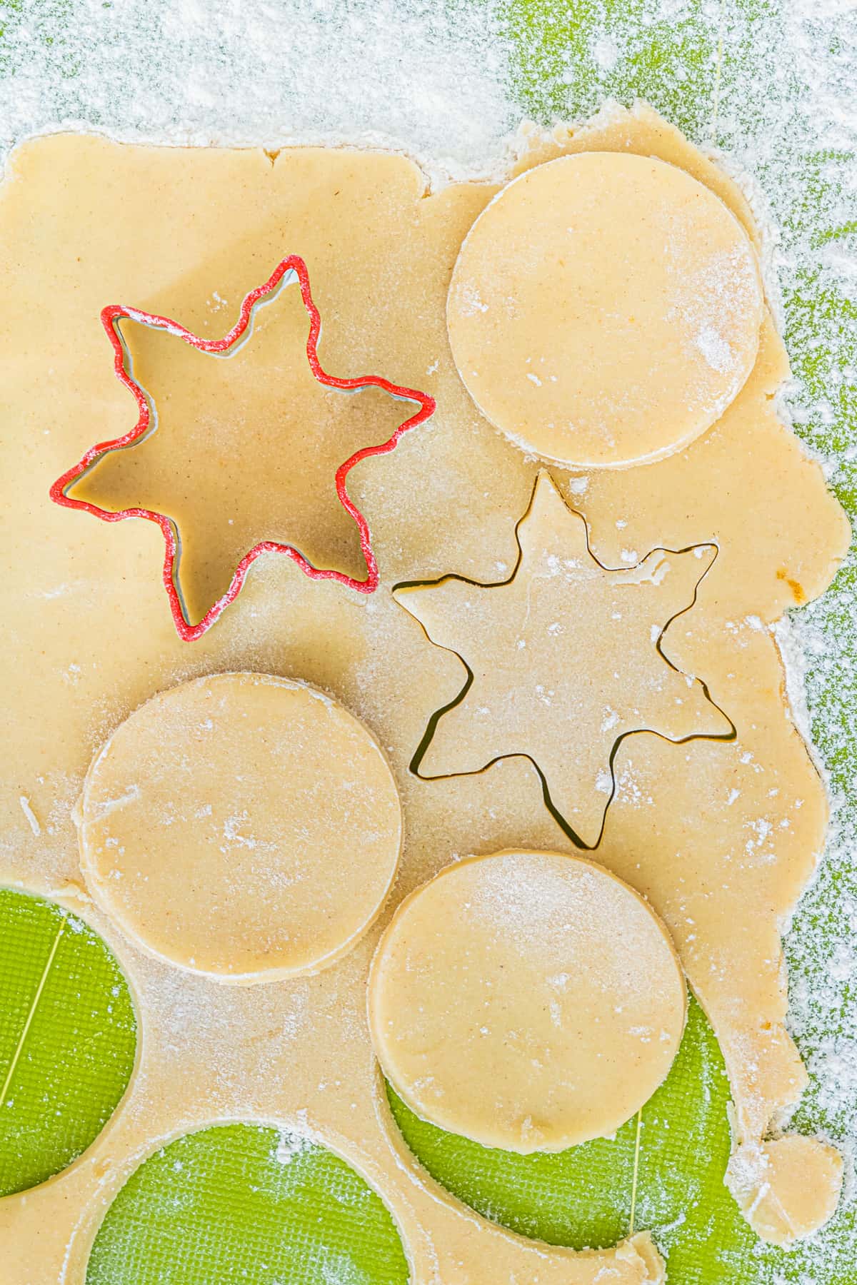 Shortbread cookies being cut with snowflake and circle cookie cutters