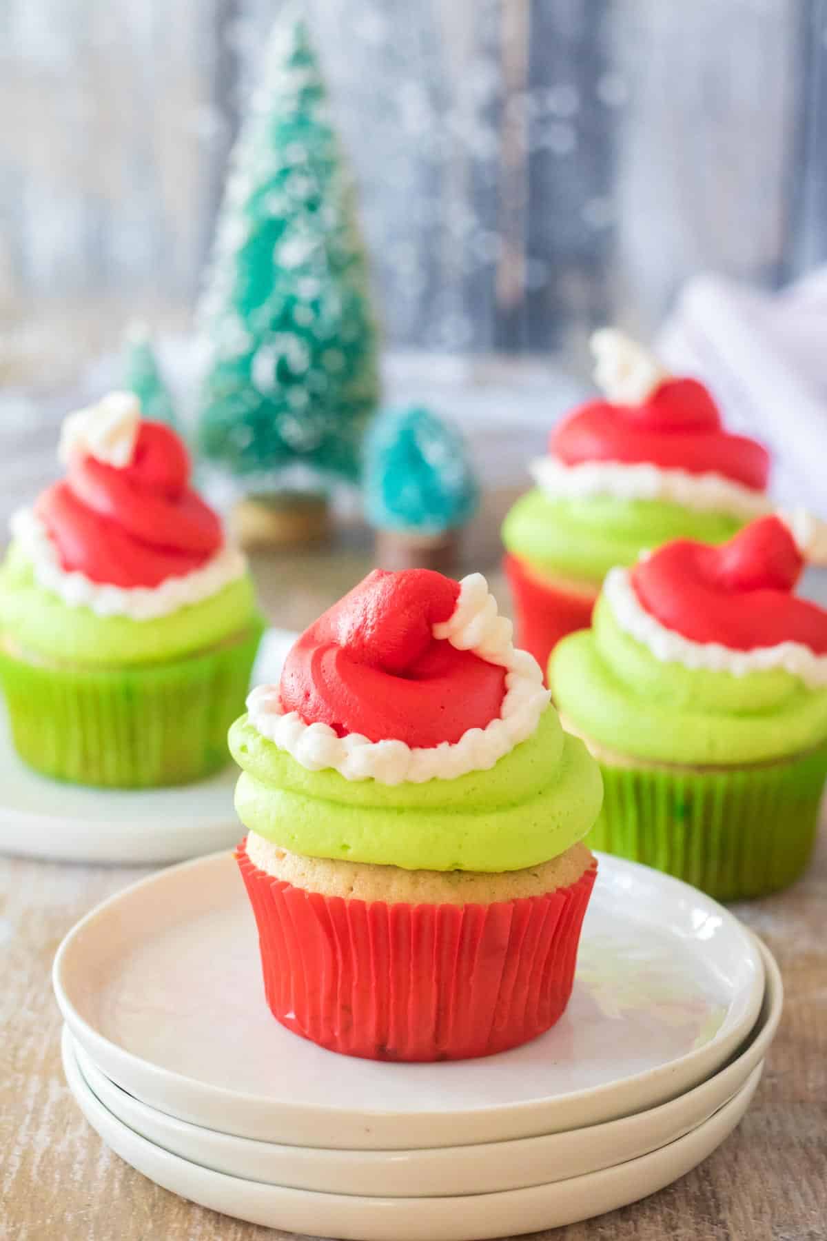 Grinch Cupcakes with green frosting and red and white frosting santa hats