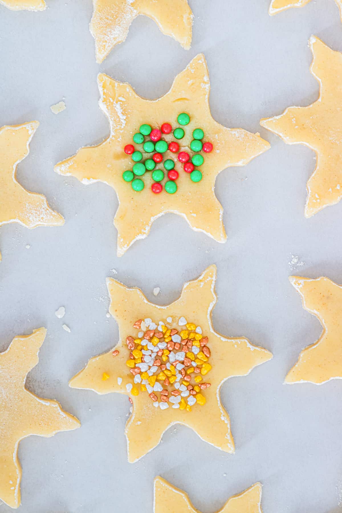 Snowflake shortbread cookies with sprinkles on top on lined baking sheet