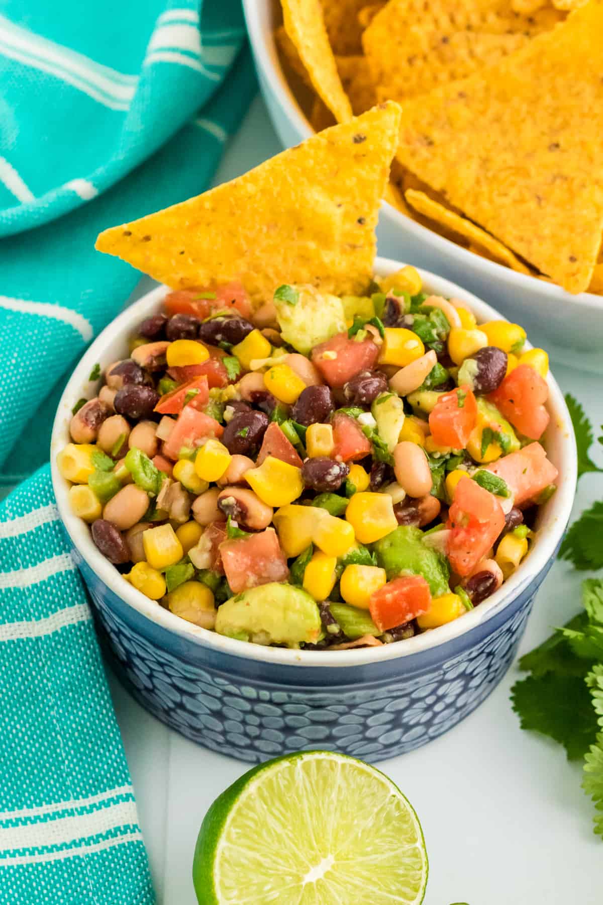 Cowboy Caviar dip with beans, avocado, corn, tomatoes, scallions, and dressing in a bowl, served with tortilla chips