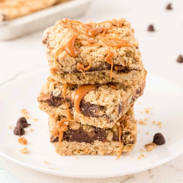 Carmelitas Cookies with sticky caramel oozing out sliced into squares and stacked on top of each other on a white plate