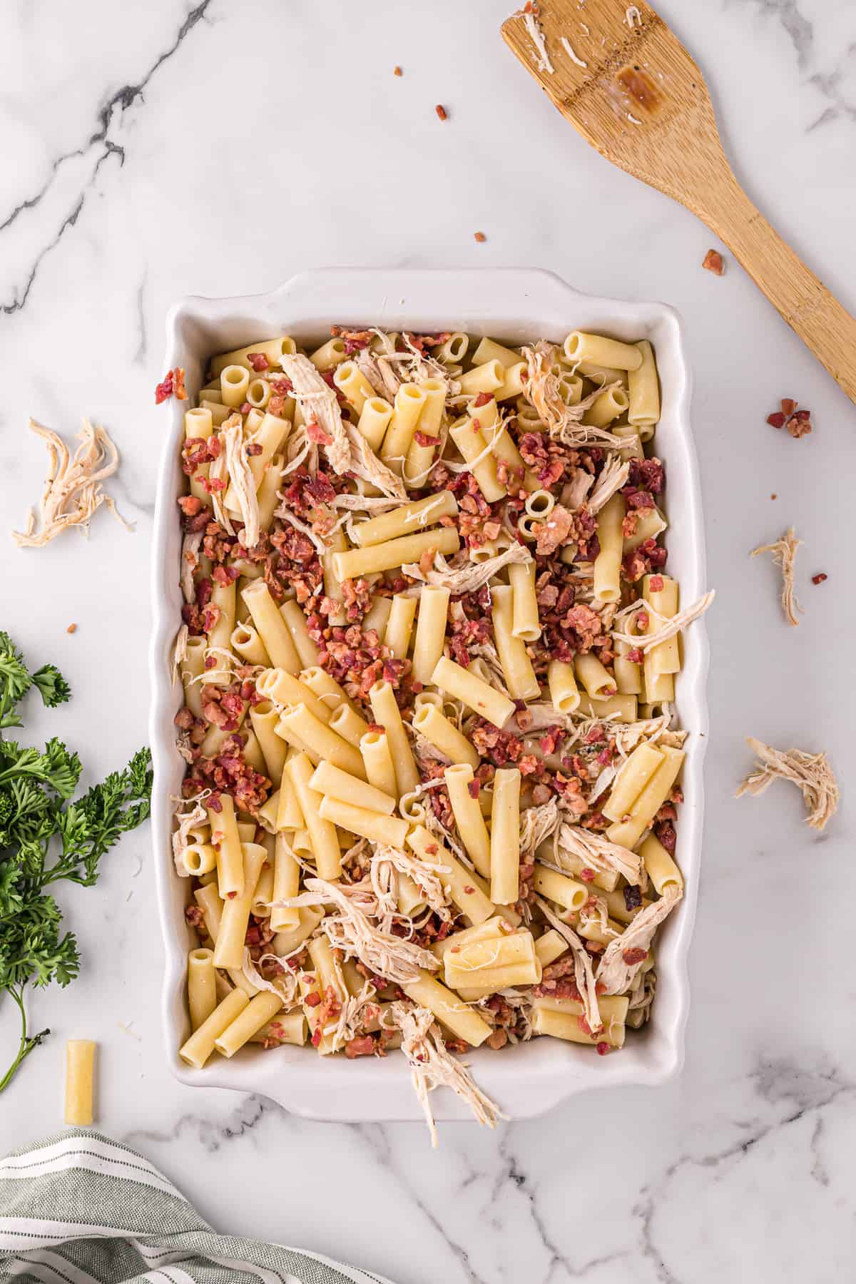 Casserole dish with ziti, crumbled bacon, shredded cooked chicken