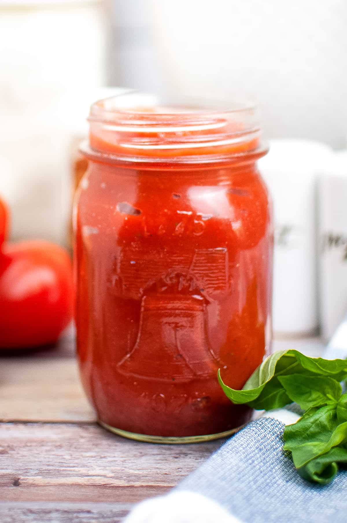 Homemade pizza sauce from tomato pasta in a mason jar on a wooden table.